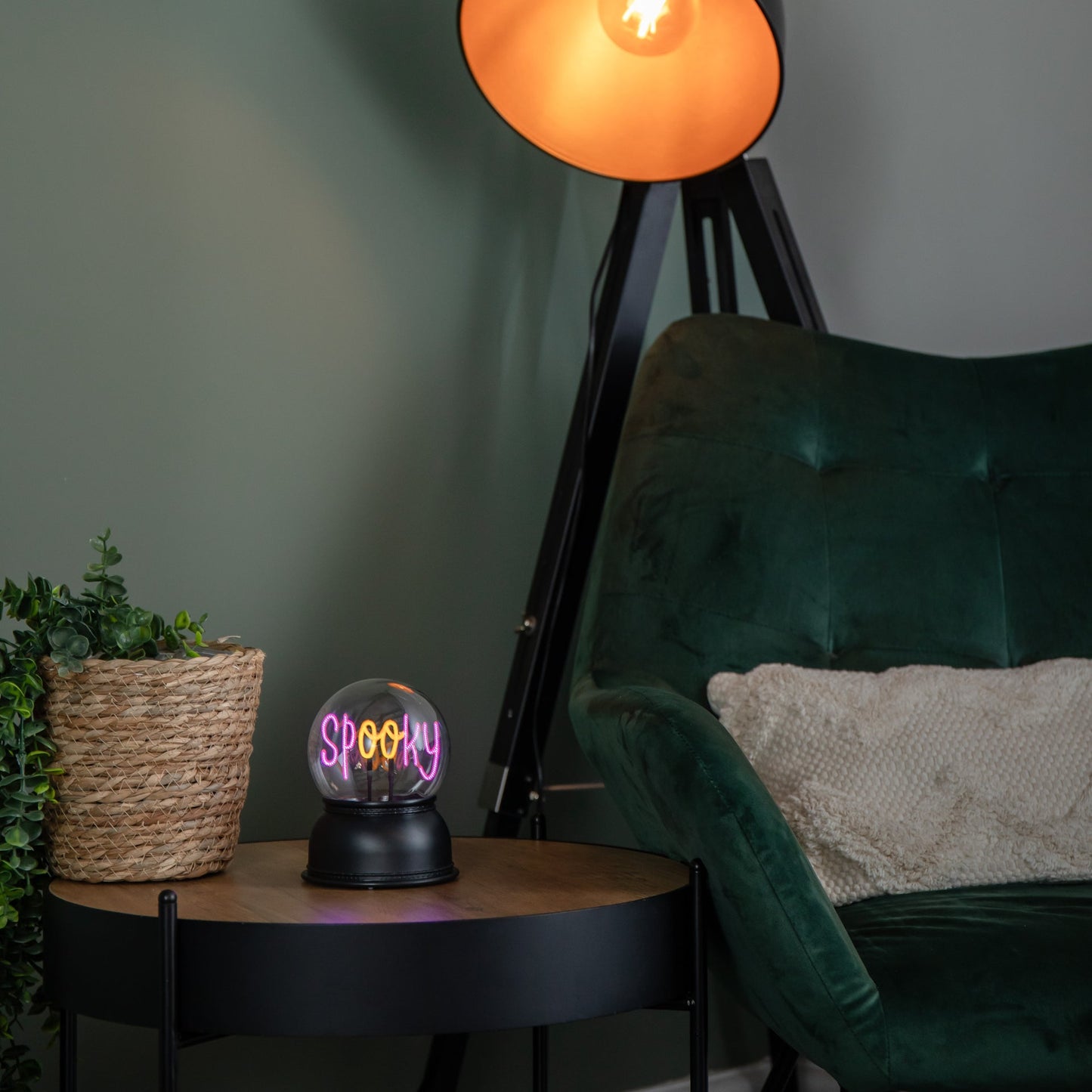 Front view of the 14cm Samuel Alexander spooky Halloween globe illuminating the word SPOOKY with a purple and orange LED light on a wooden table.