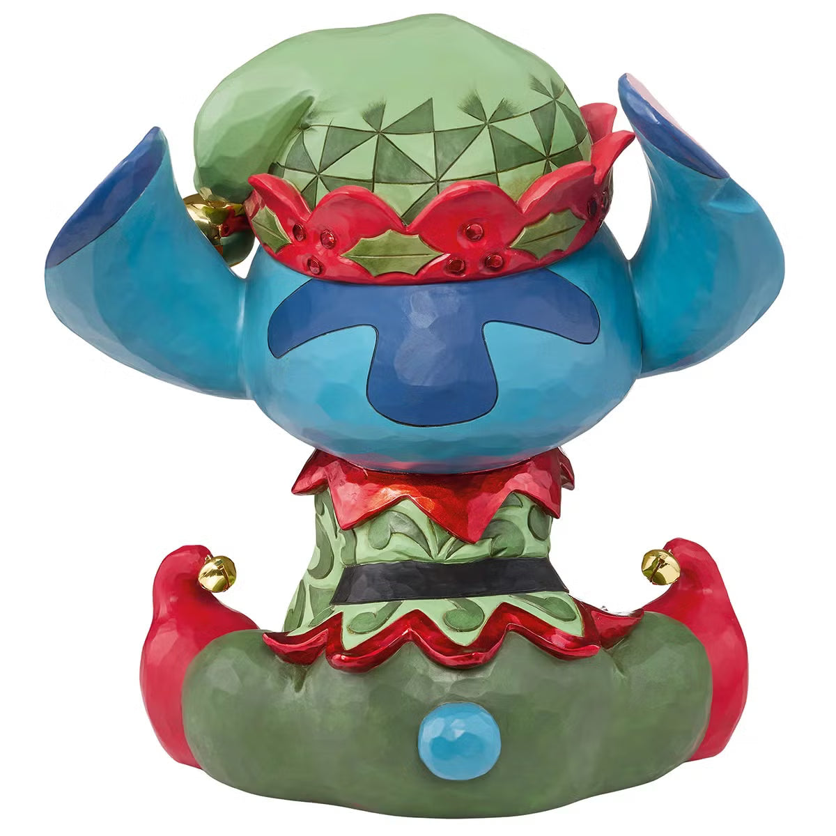 Front angle view of a 14-inch hand-painted Disney Elf Stitch statue by Jim Shore featuring green elf hat, jingle bells, and detailed stone resin folk patterns on a wooden table.