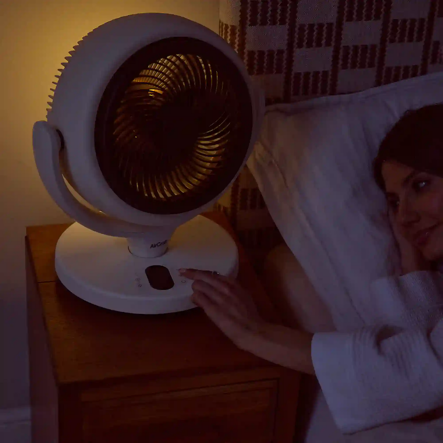 AirCraft LUME MINI white table air circulator fan with magnetic remote control on a modern bedside table.
