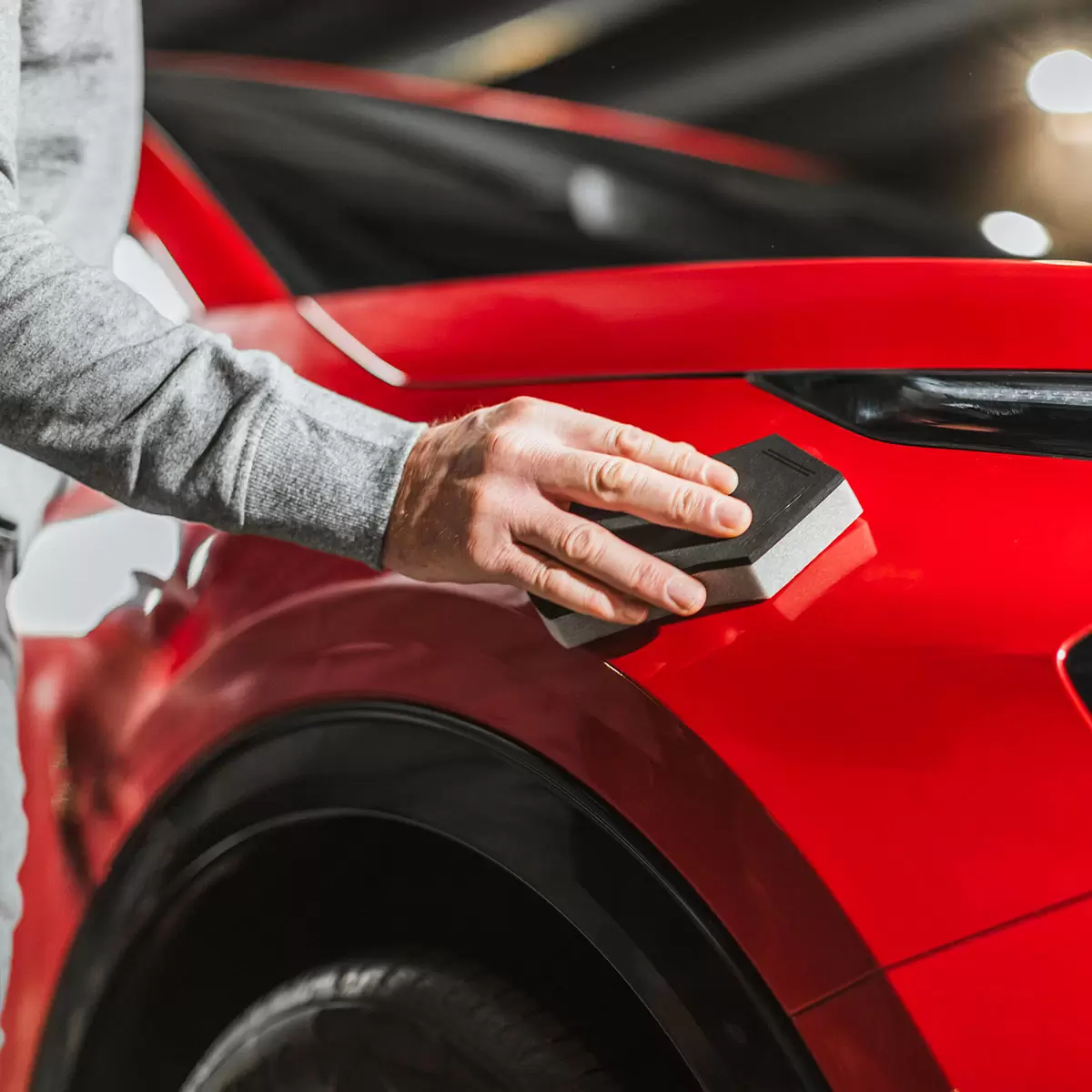 Autoglym Super Resin Polish 3 piece kit featuring a 500ml bottle, red applicator sponge, and grey microfiber cloth set against a glossy car bonnet.