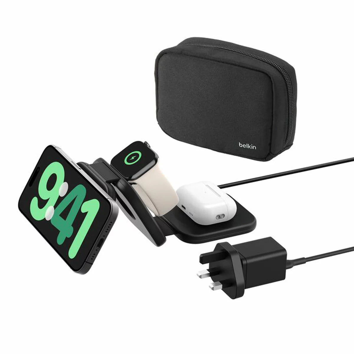 A black foldable Belkin BoostCharge Pro 3-in-1 charging pad laid out flat on a hotel desk, wirelessly charging an iPhone, Apple Watch, and AirPods case.