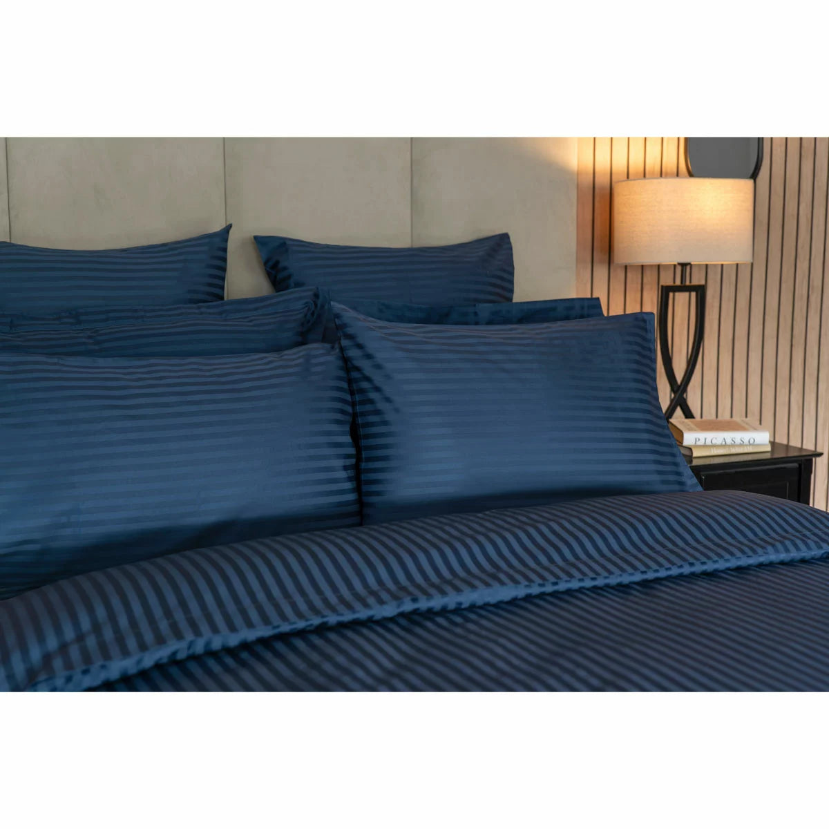 Flat lay image of the Belledorm 540 thread count navy satin stripe duvet cover set with matching pillowcases neatly arranged on a modern wooden bed.