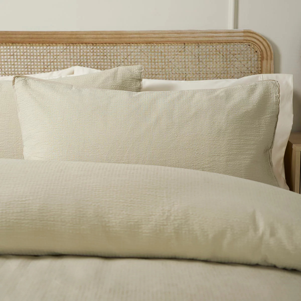 A close-up angle of the Belledorm Avantika natural cotton bedding set showcasing its textured stippled surface and clean edge seams in a neutral-toned master bedroom.