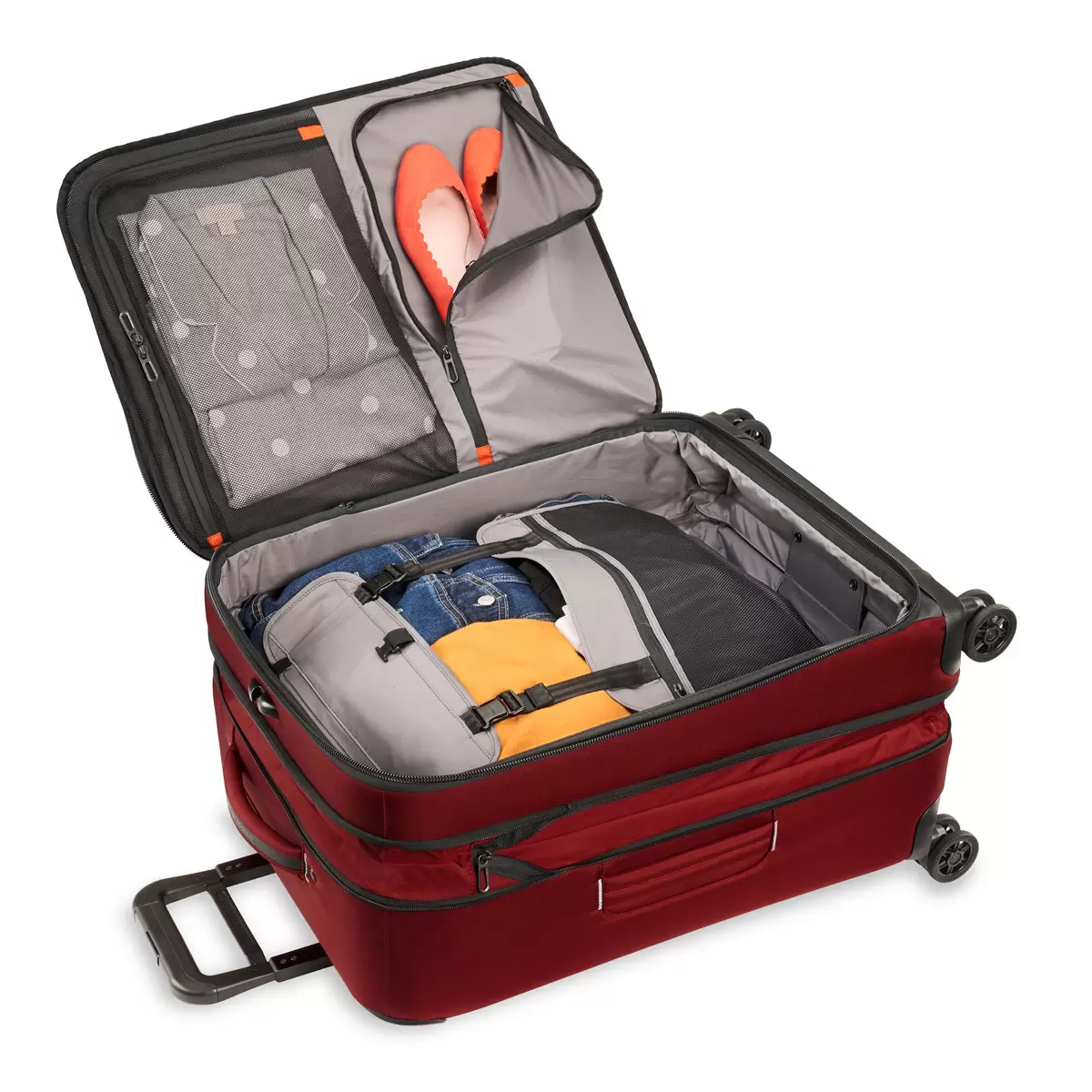 Three-quarter angle view of the black Briggs & Riley ZDX 66cm Medium Expandable Spinner Suitcase highlighting its exterior handle, zip expansion, and smooth dual spinner wheels on a neutral background.