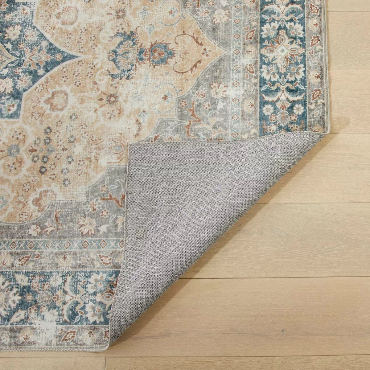 Close-up angle of the gold-patterned Concept Looms Liberty Washable Rug resting flat on a modern wood floor showing its soft 4mm velvet surface.