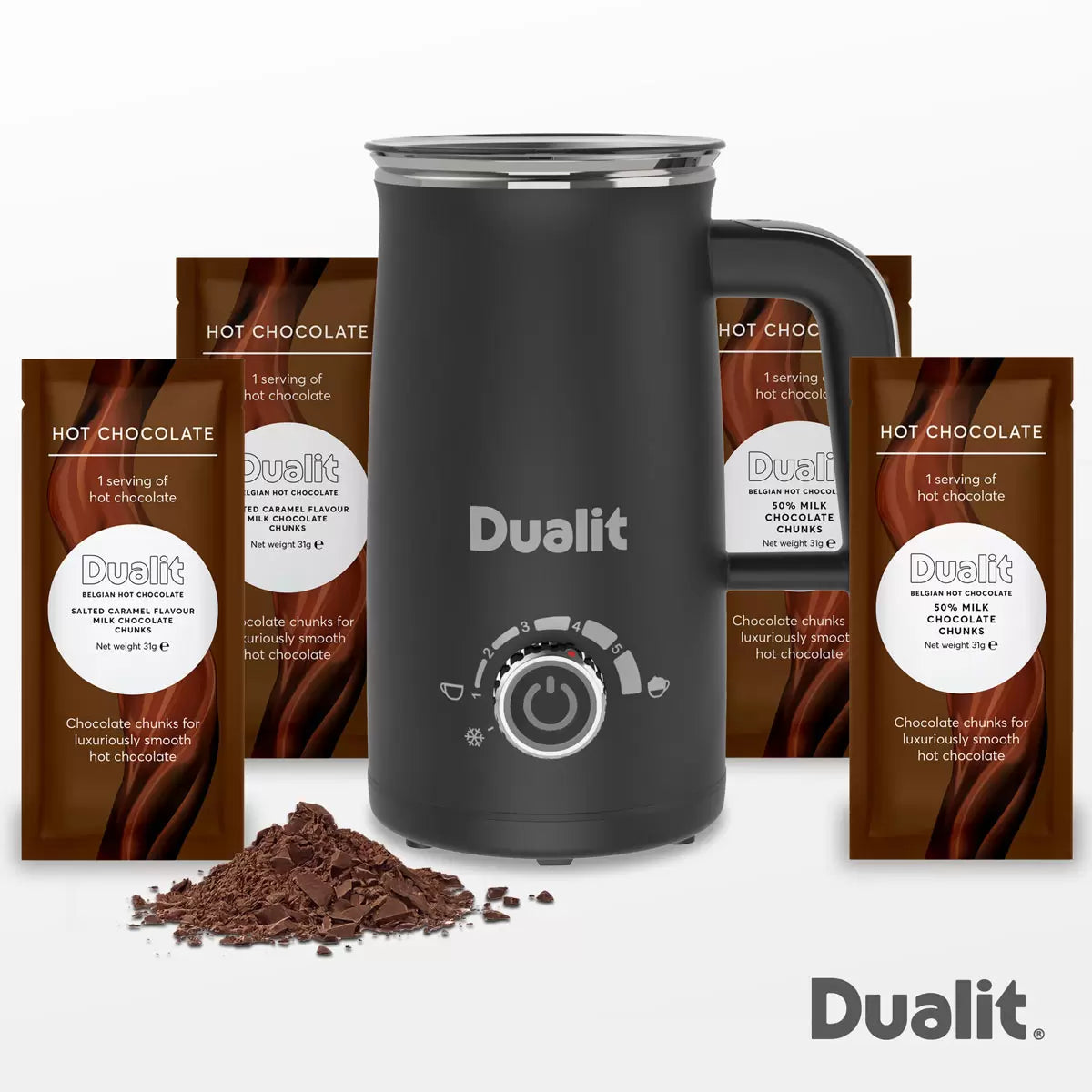Dualit Milk Frother Max in black and stainless steel sitting on a wooden kitchen counter next to a mug of hot chocolate with chocolate sachets alongside.
