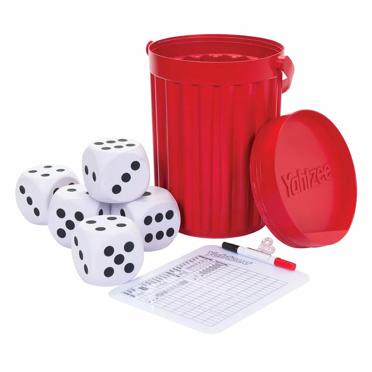 Five large wooden dice from the Eastpoint Giant Yahtzee set scattered on a green lawn next to a shaker bucket.