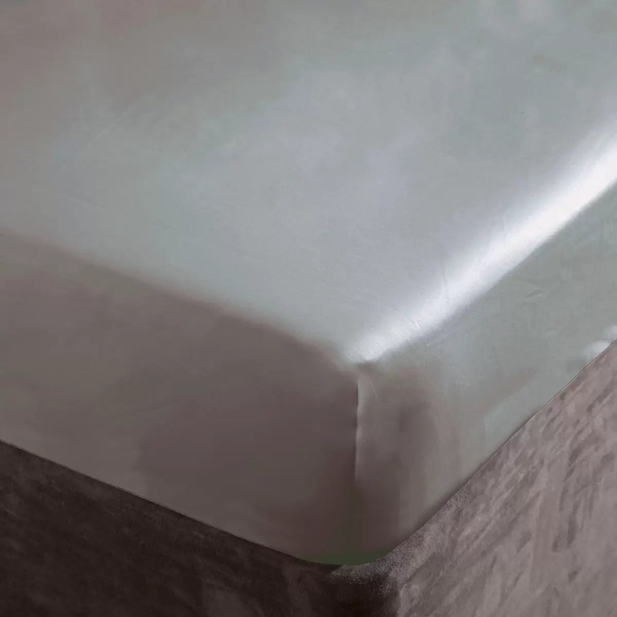 A close-up studio photograph showing the platinum silver-grey Belledorm 1000 thread count sateen fitted sheet pulled smoothly and tightly over the corner of a contemporary mattress.