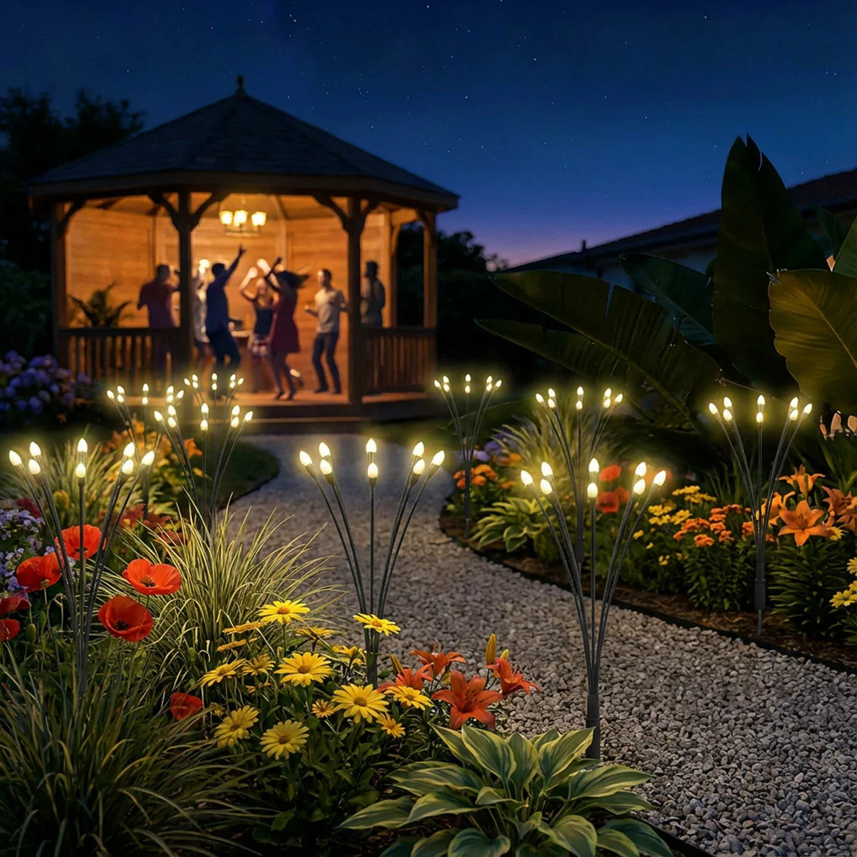 Four-pack of Fresh Source Solar Firefly Lights with warm LED bulbs installed in a lush garden flowerbed during twilight.