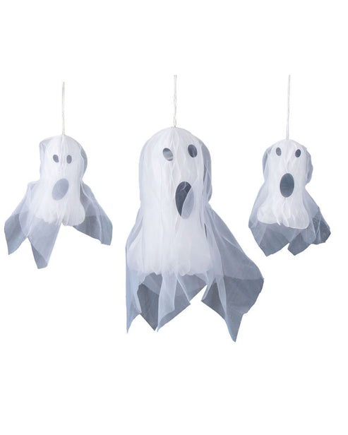 Three white hanging honeycomb tissue paper ghosts suspended against a dark wall in a dimly lit home entryway.