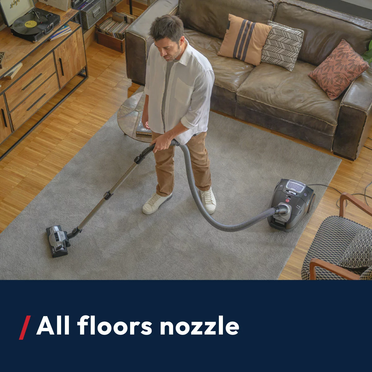 Compact red and grey Hoover H-ENERGY 500 cylinder vacuum cleaner HE520PET positioned on a living room rug with its pet turbo tool attachment displayed alongside.
