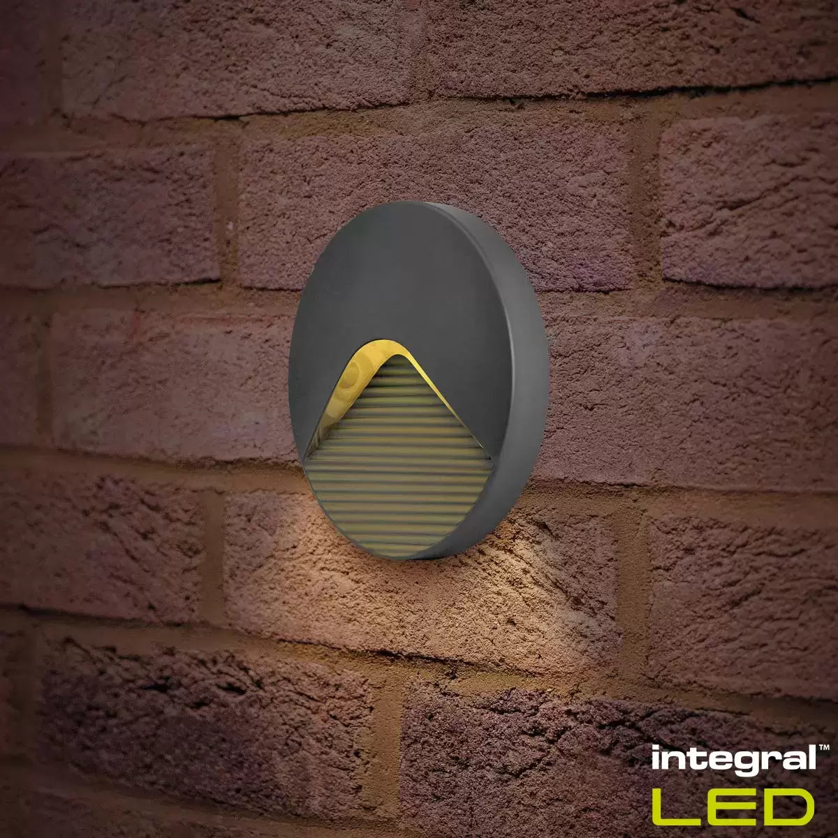 Two Integral Pathlux step lights mounted low on a stone garden wall, casting a soft pool of light onto dark stone stairs.