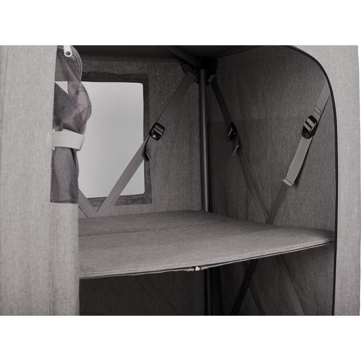 A sleek grey Kampa Hollow folding camping cupboard standing inside a large tent, showing its two fabric shelves packed with neatly folded clothes and a lantern resting on its solid top side table surface.