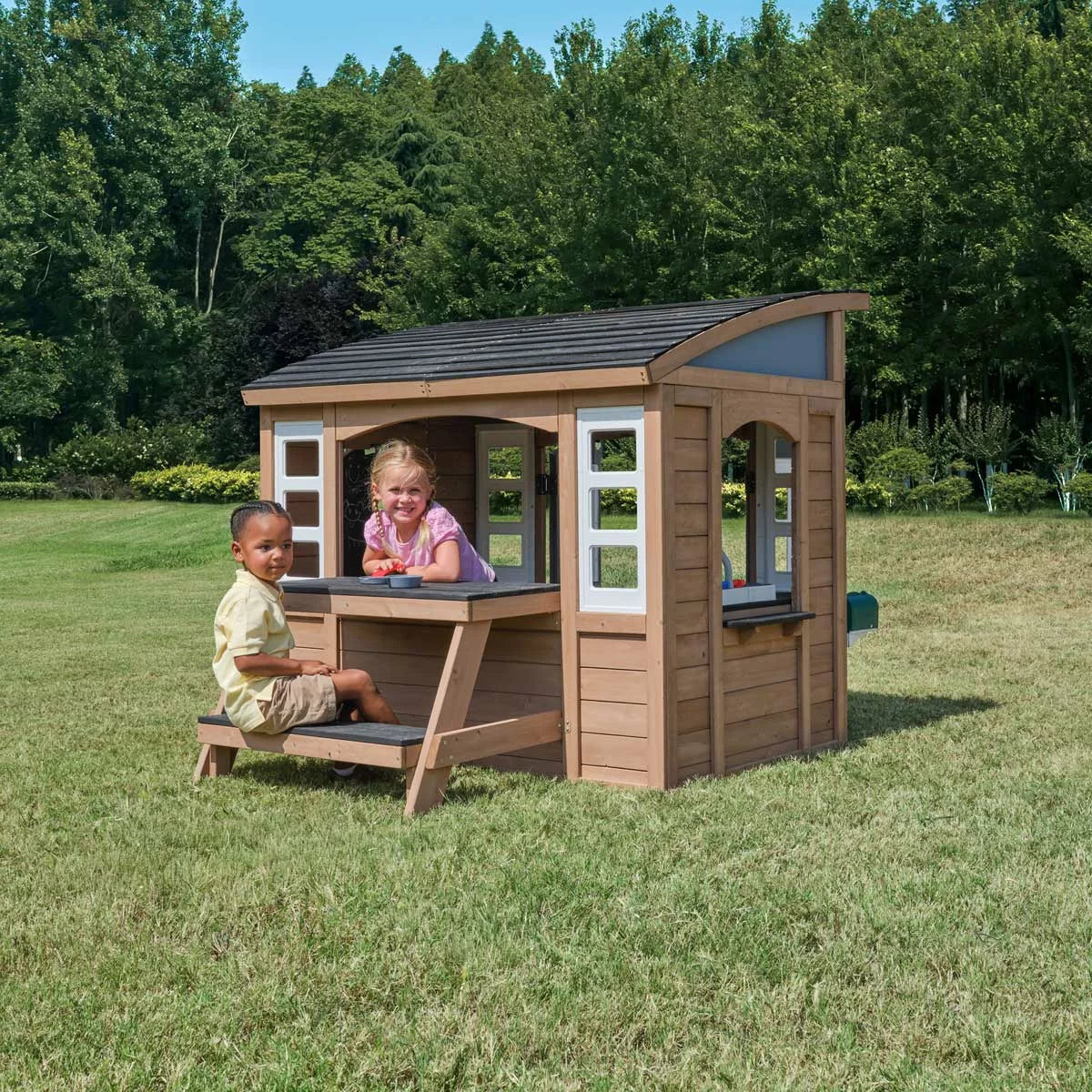 KidKraft Sunny Bluff brown wooden outdoor playhouse with curved double doors, picnic table, kitchen area, chalkboard shutters, and garden play space for children-3