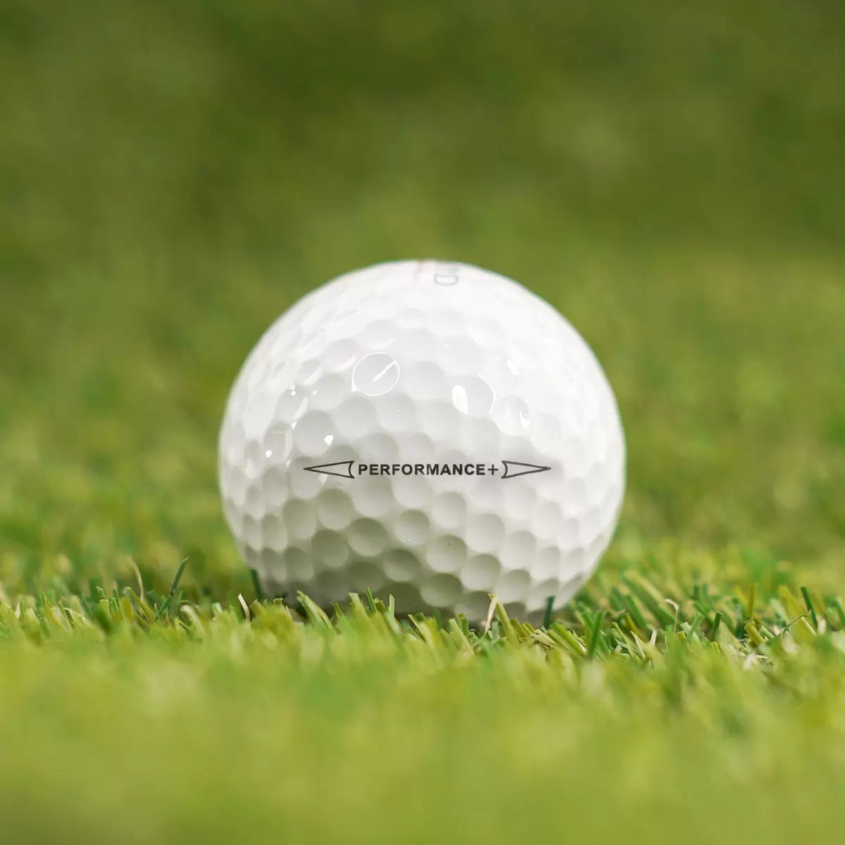 High-angle studio shot of two dozen white Kirkland Signature 3-piece urethane golf balls arranged neatly inside their distinct red and black packaging on a dark reflective surface.