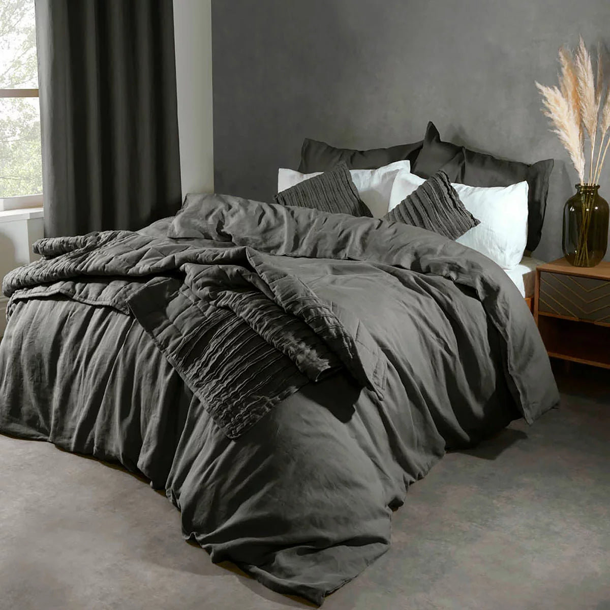 Flat lay photo of the Lazy Linen 100% washed charcoal grey linen duvet cover set neatly dressed on a king bed, showing its soft relaxed texture and matching button-closure pillowcases.