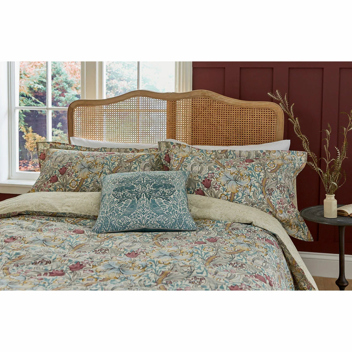 A styled bedroom scene displaying the Morris & Co. Golden Lily duvet cover set on a king size bed, showcasing the intricate green and yellow botanical tendrils and matching Oxford pillowcases.