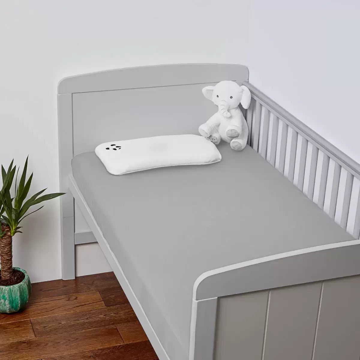 A close-up view of two folded Panda bamboo cot fitted sheets showing the silky, organic knit texture in a soft nursery setting.