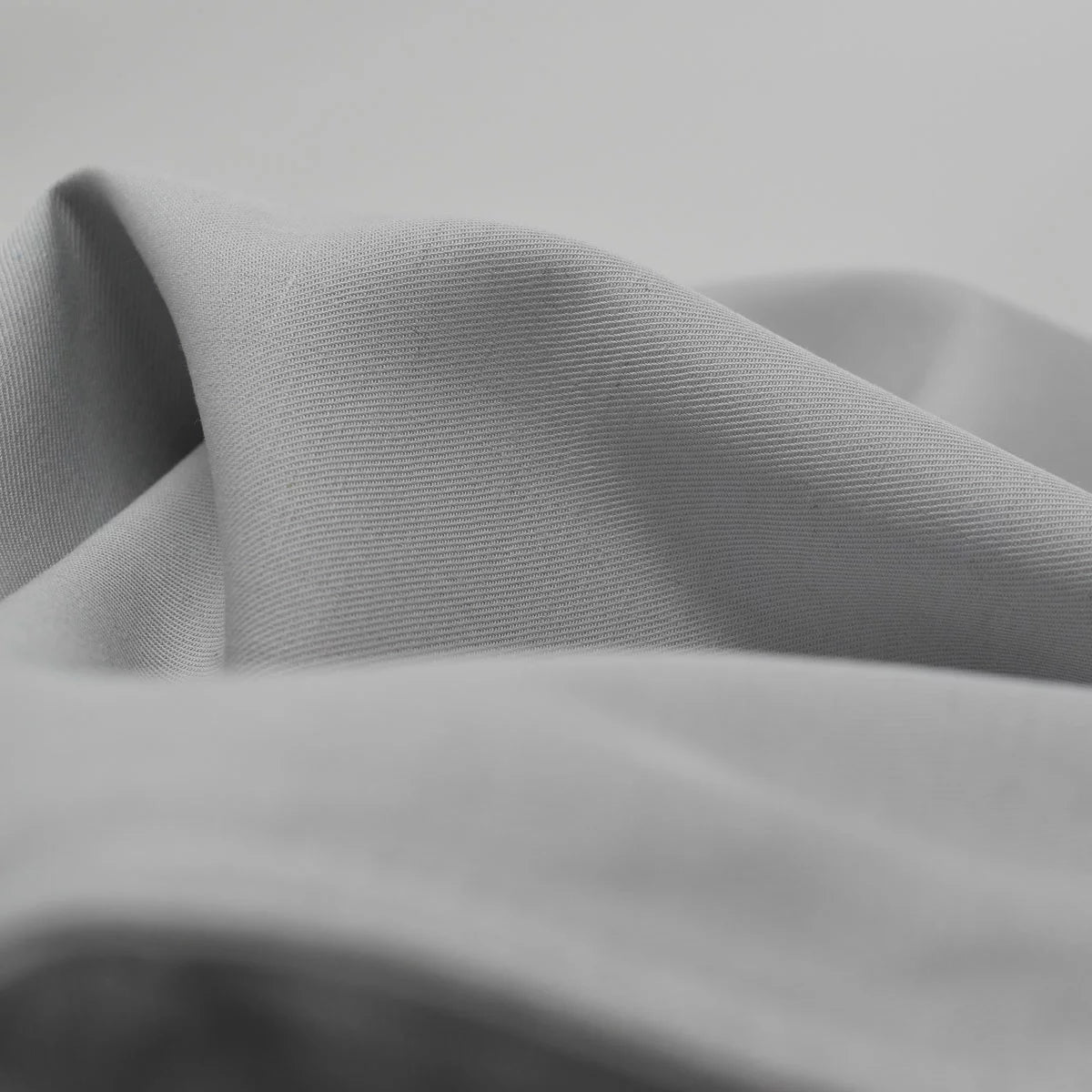 Neutral grey Panda bamboo and French linen fitted sheet pulled taut over the corner of a deep mattress showcasing its textured matte finish.