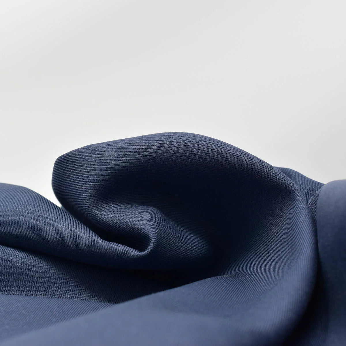 Deep navy blue Panda bamboo and French linen fitted sheet wrapped tight around the corner of a thick mattress showing its textured matte finish.