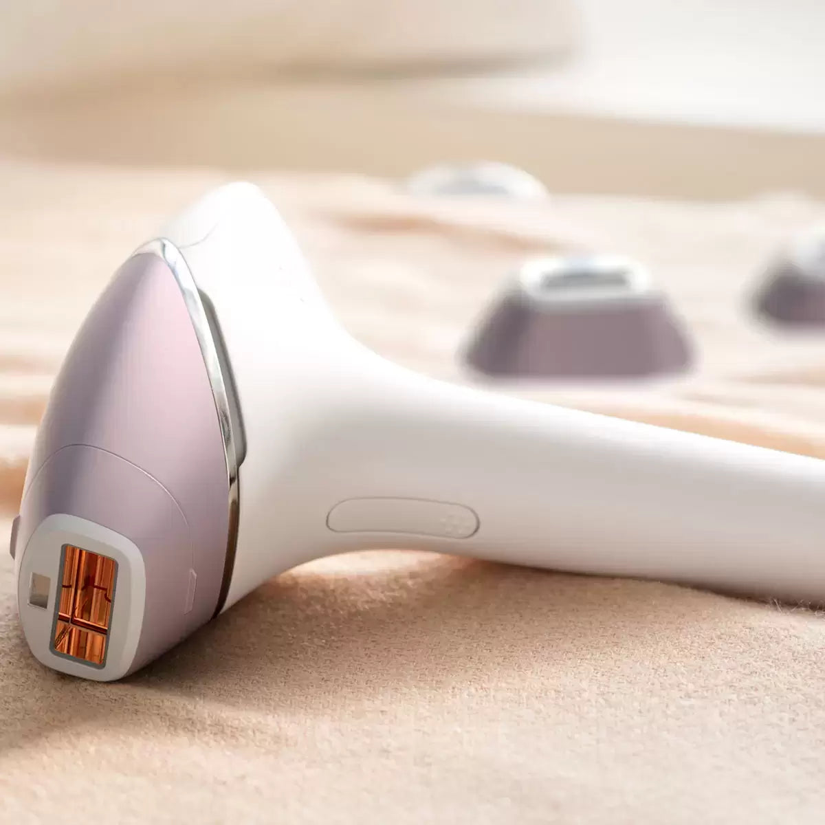 The Philips Lumea Prestige IPL device in a sleek white finish resting next to its four specialized treatment attachments and storage pouch on a clean, modern vanity surface.
