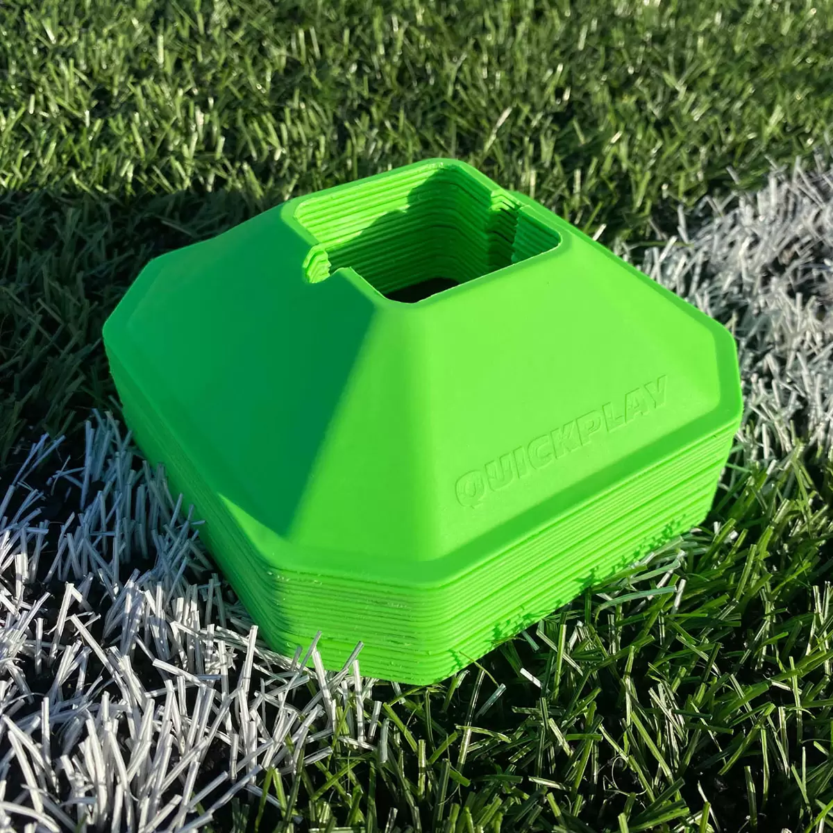 Complete Quickplay Kickster training kit set up on a manicured green grass pitch featuring the black and yellow frame goal, a Size 3 football, and bright orange mini cones spaced for agility drills.