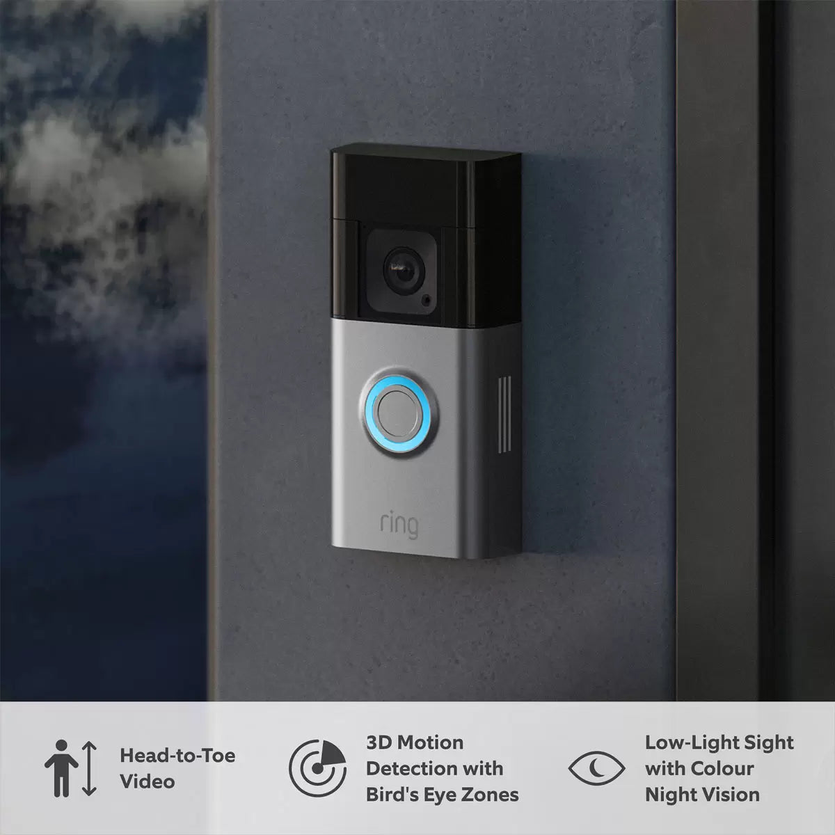 A satin nickel Ring Battery Video Doorbell Pro mounted next to a wooden front door, showing the wide lens perspective, beside a compact white Chime plugged into a hallway socket.