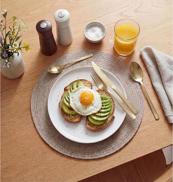Top-down view of the 32-piece Russell Hobbs Vienna gold satin stainless steel cutlery set neatly arranged on a dark wooden table setting.