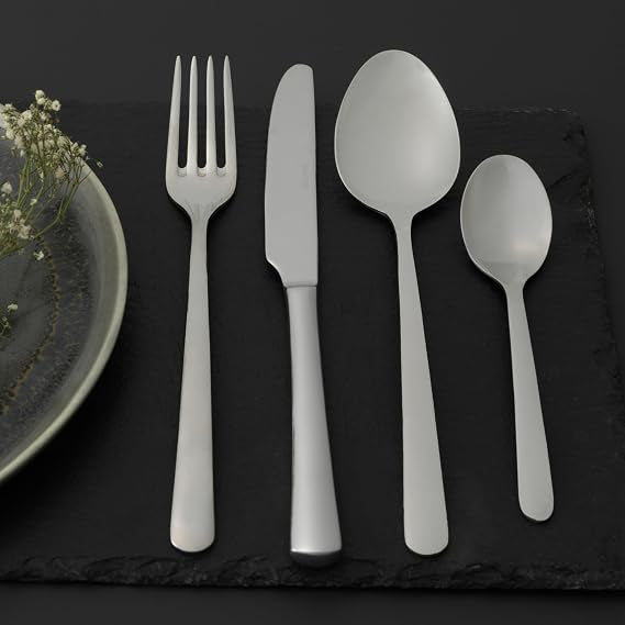 Salter Kendal 32 piece mirror polished silver cutlery set arranged neatly on a wooden dining table including forks knives tablespoons and teaspoons.