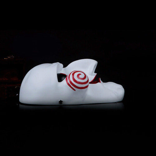 Front view of a white Saw Billy puppet horror mask with red spiral cheek details and red lips on a black background.