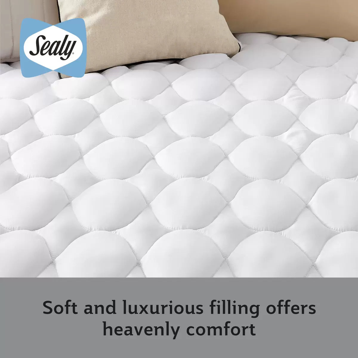 Close-up view of the white Sealy Deeply Full Mattress Topper showing corner elastic straps and stitched microfibre detail on a dressed bed.