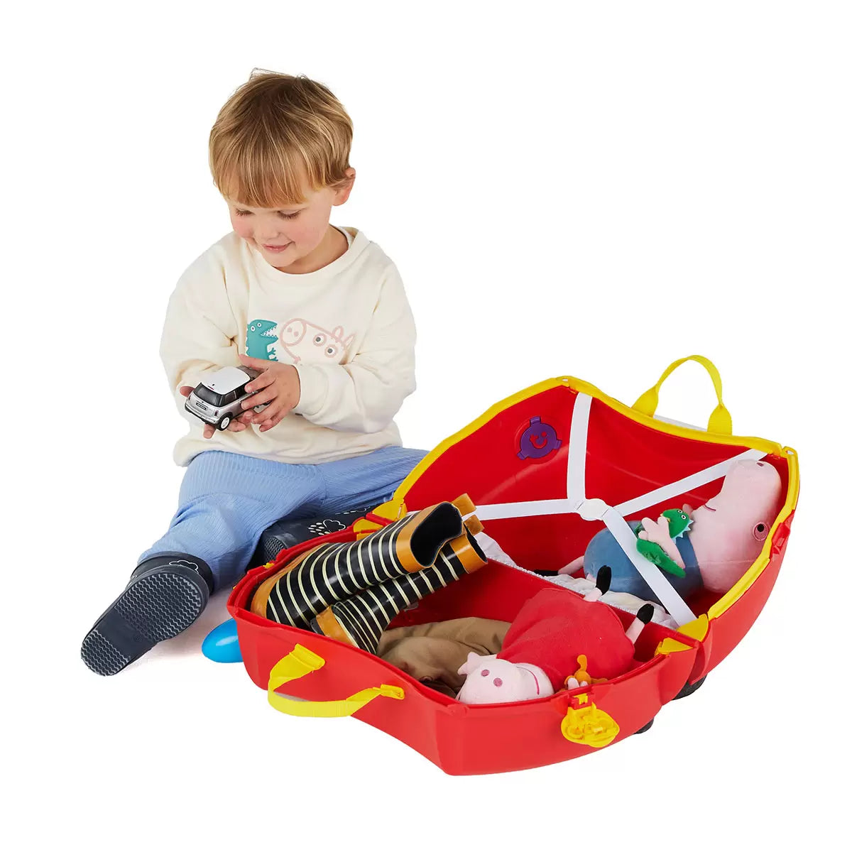 The Trunki Peppa Pig Party Bus ride-on suitcase in bright red with Peppa Pig branding, displayed on a clean studio floor to show its wheels and steering horns.