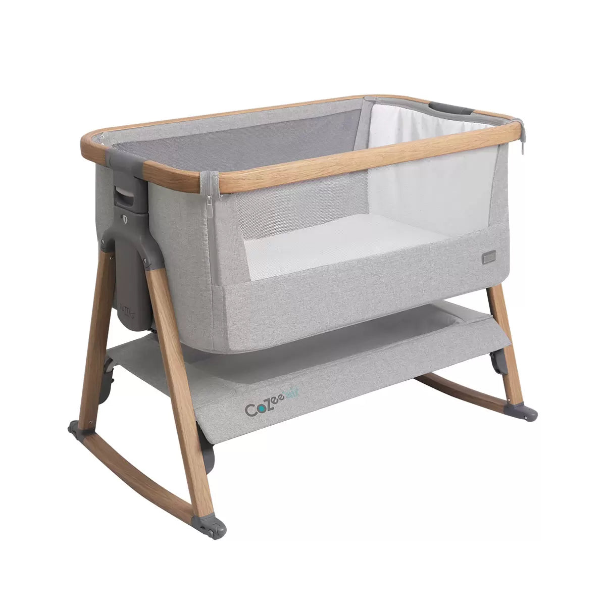 Side view of the Tutti Bambini CoZee Air bedside crib in oak and silver finish showing dual mesh windows, mattress, and detachable rocking arches inside a neutral nursery.