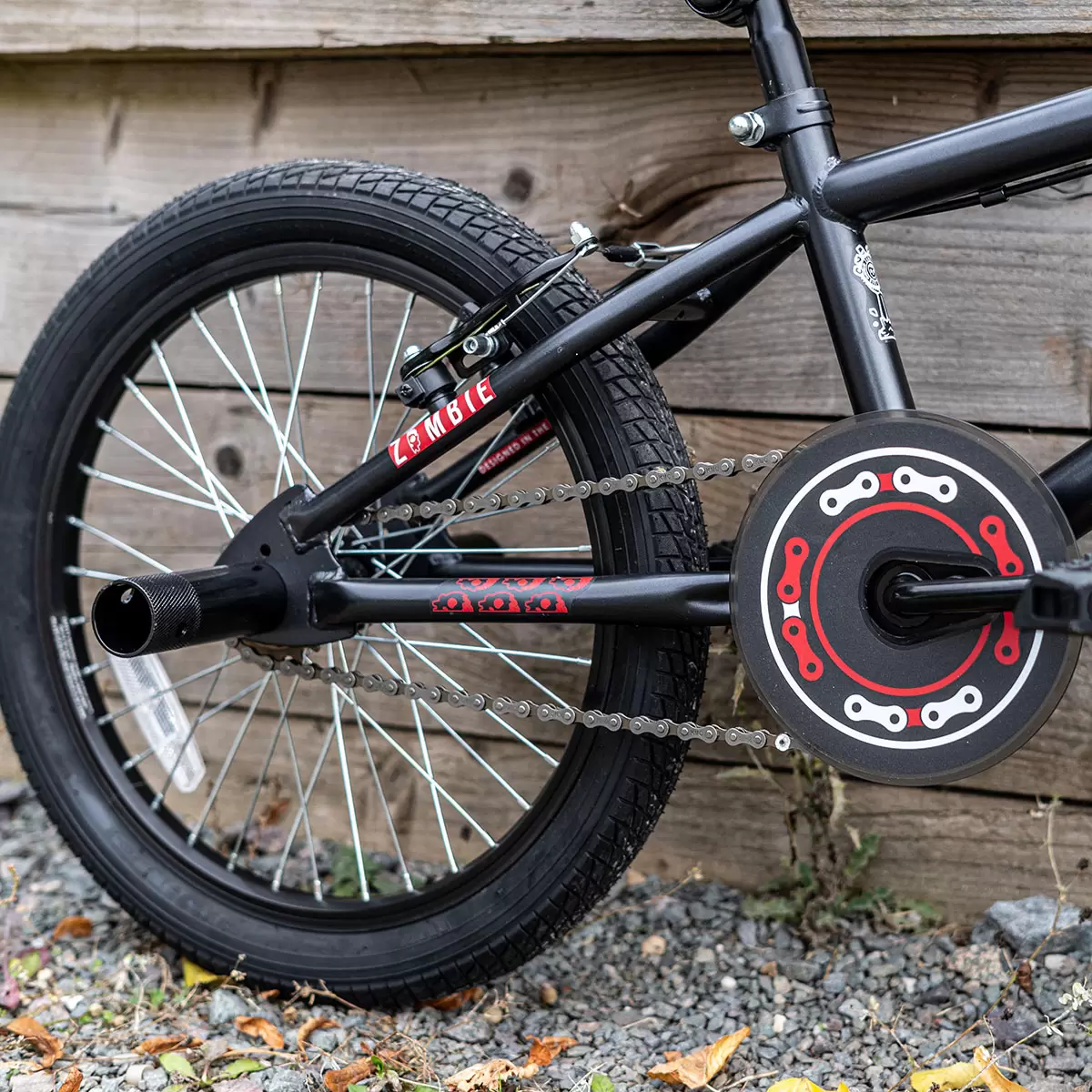 Side profile of the black Zombie Plague 18-inch junior BMX bike showing the 10-inch steel frame, alloy wheels, and installed rear stunt peg on a concrete surface.