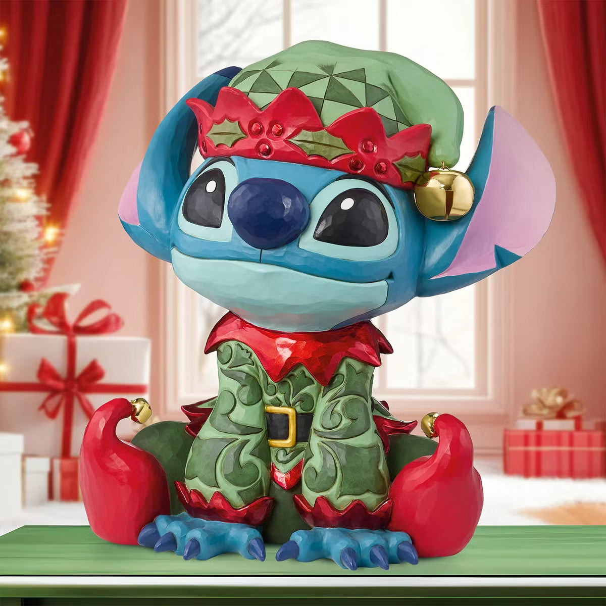 Front angle view of a 14-inch hand-painted Disney Elf Stitch statue by Jim Shore featuring green elf hat, jingle bells, and detailed stone resin folk patterns on a wooden table.
