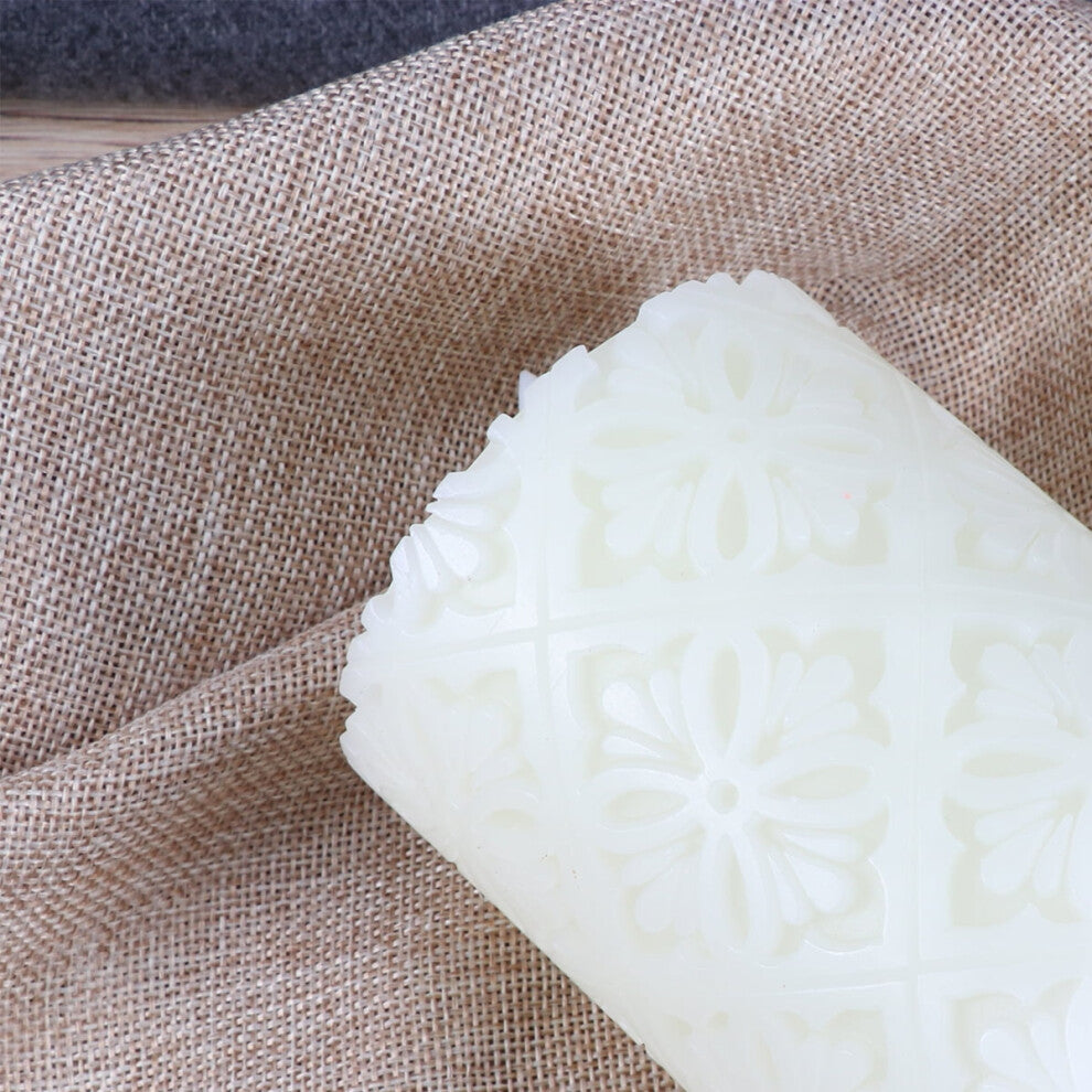 A 15cm white paraffin wax flameless LED candle featuring an intricate hollow flower pattern glowing softly on a decorative table.