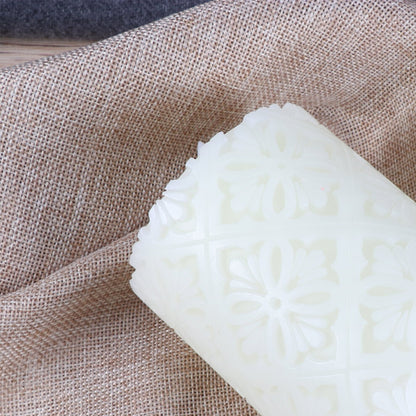 A 15cm white paraffin wax flameless LED candle featuring an intricate hollow flower pattern glowing softly on a decorative table.
