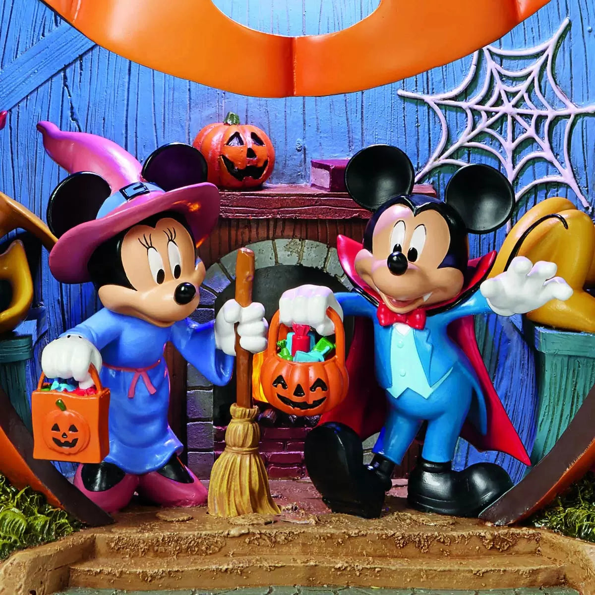 Hand-crafted 16 inch orange Disney pumpkin house illuminated with internal LED lights featuring detailed Mickey and Friends figurines on an entryway console table.