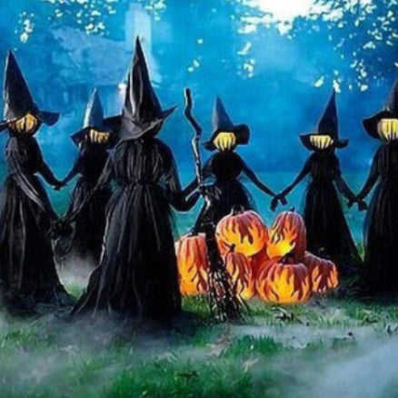Front view of three 170cm life-size faceless witches in black robes holding hands on a dark lawn with glowing heads flickering in the dark.
