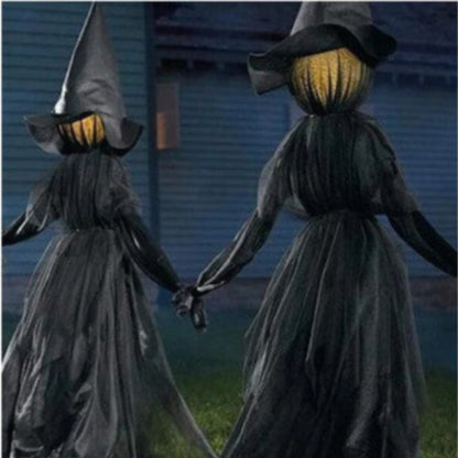 Front view of three 170cm life-size faceless witches in black robes holding hands on a dark lawn with glowing heads flickering in the dark.