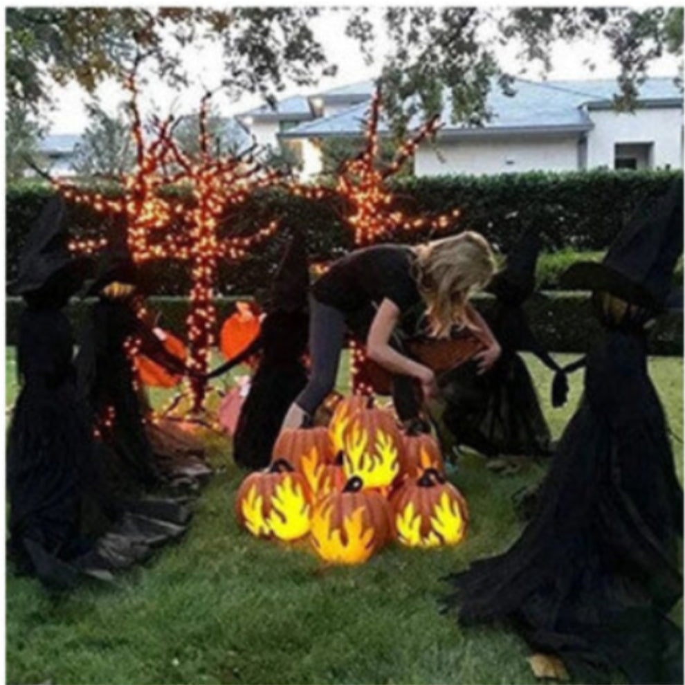 Front view of three 170cm life-size faceless witches in black robes holding hands on a dark lawn with glowing heads flickering in the dark.