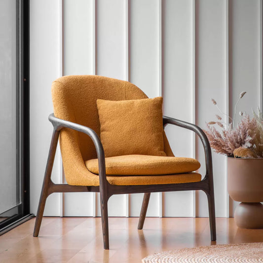 A front-three-quarter view of the Gallery Alegra ochre fabric armchair, showcasing its curved dark wood frame and vibrant textured yellow cushions in a modern living room corner.