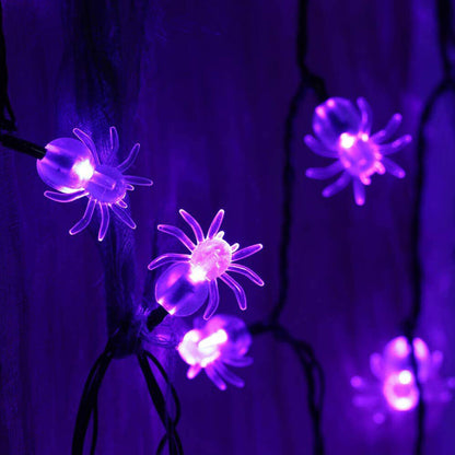 A 20ft string of 40 purple spider-shaped LED lights glowing against an outdoor garden fence at night.