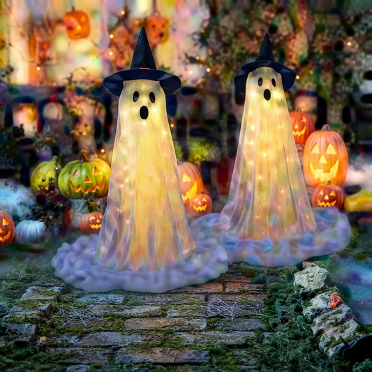 A pair of tall outdoor Halloween spooky ghost decorations illuminated by remote-controlled string lights on a dark lawn during evening hours.