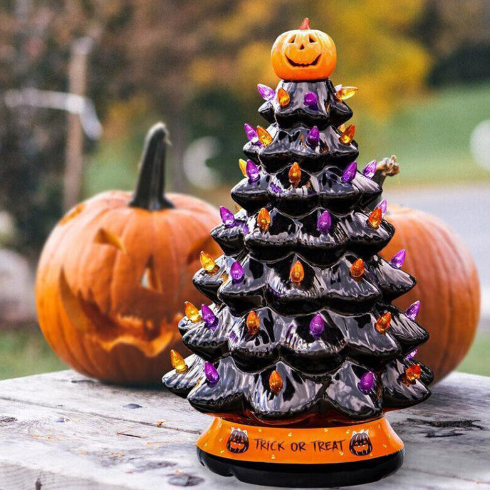A 30cm black tabletop Halloween tree decorated with glowing pumpkin LED lights and warm white flashing beads sitting on a festive wooden surface.