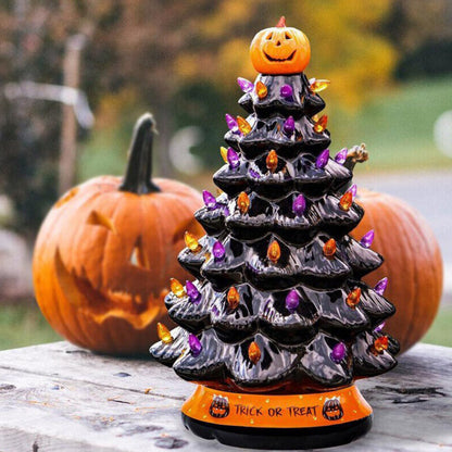 A 30cm black tabletop Halloween tree decorated with glowing pumpkin LED lights and warm white flashing beads sitting on a festive wooden surface.