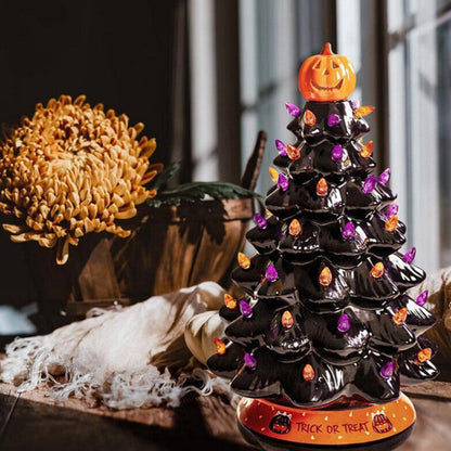 A 30cm black tabletop Halloween tree decorated with glowing pumpkin LED lights and warm white flashing beads sitting on a festive wooden surface.