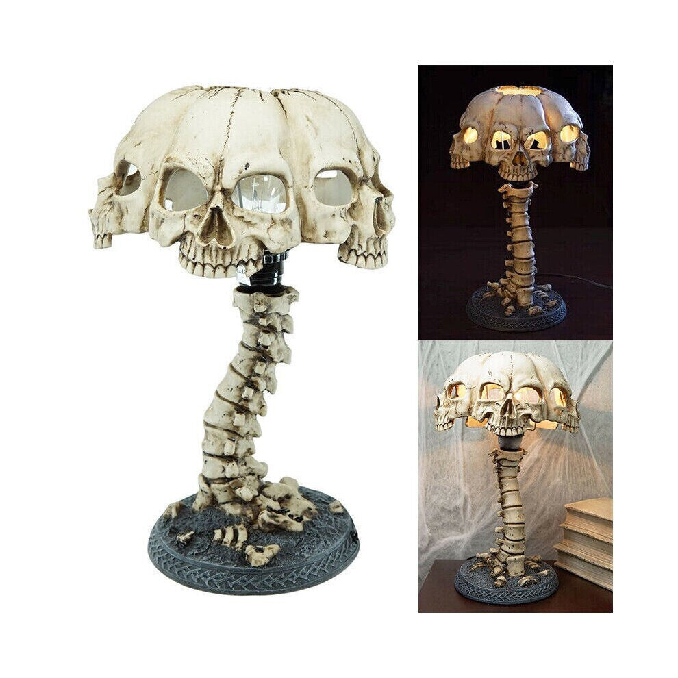 A hand-painted 3D resin skull skeleton desk lamp glowing with eerie light on a dark wooden table decorated for Halloween.
