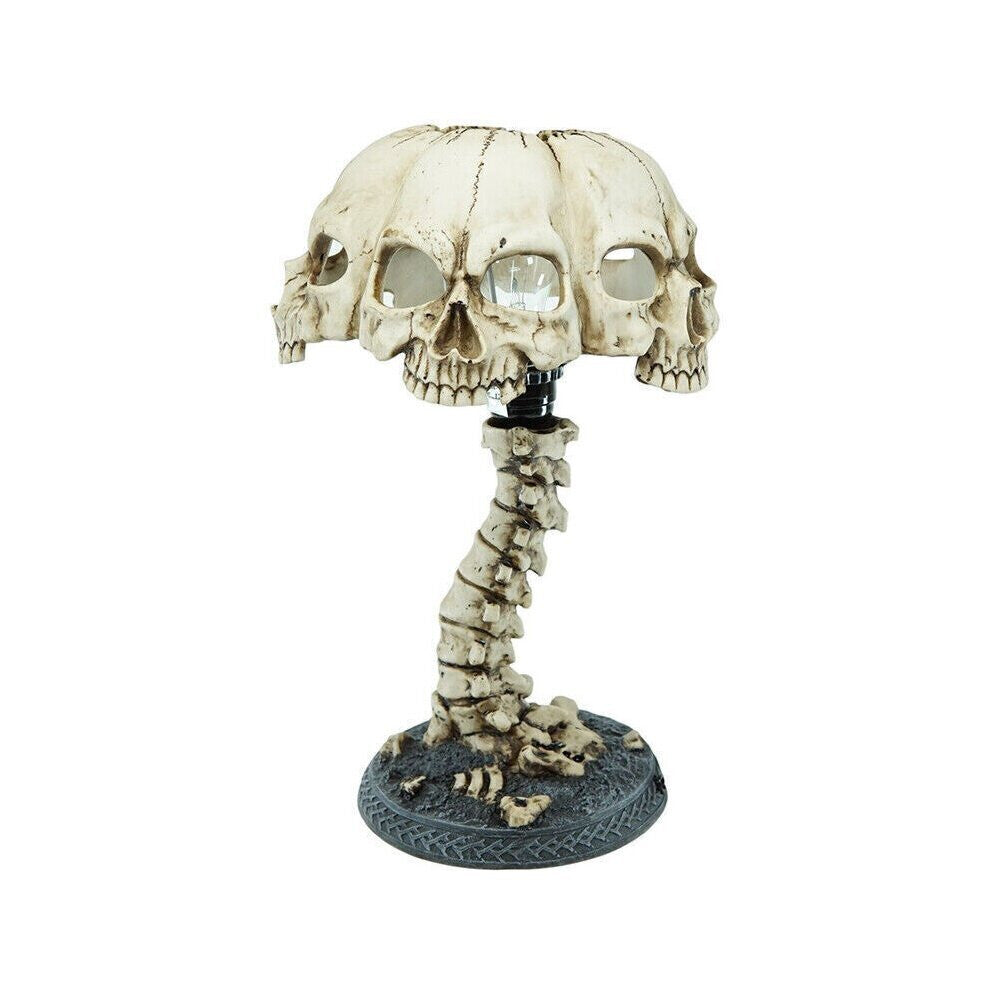A hand-painted 3D resin skull skeleton desk lamp glowing with eerie light on a dark wooden table decorated for Halloween.