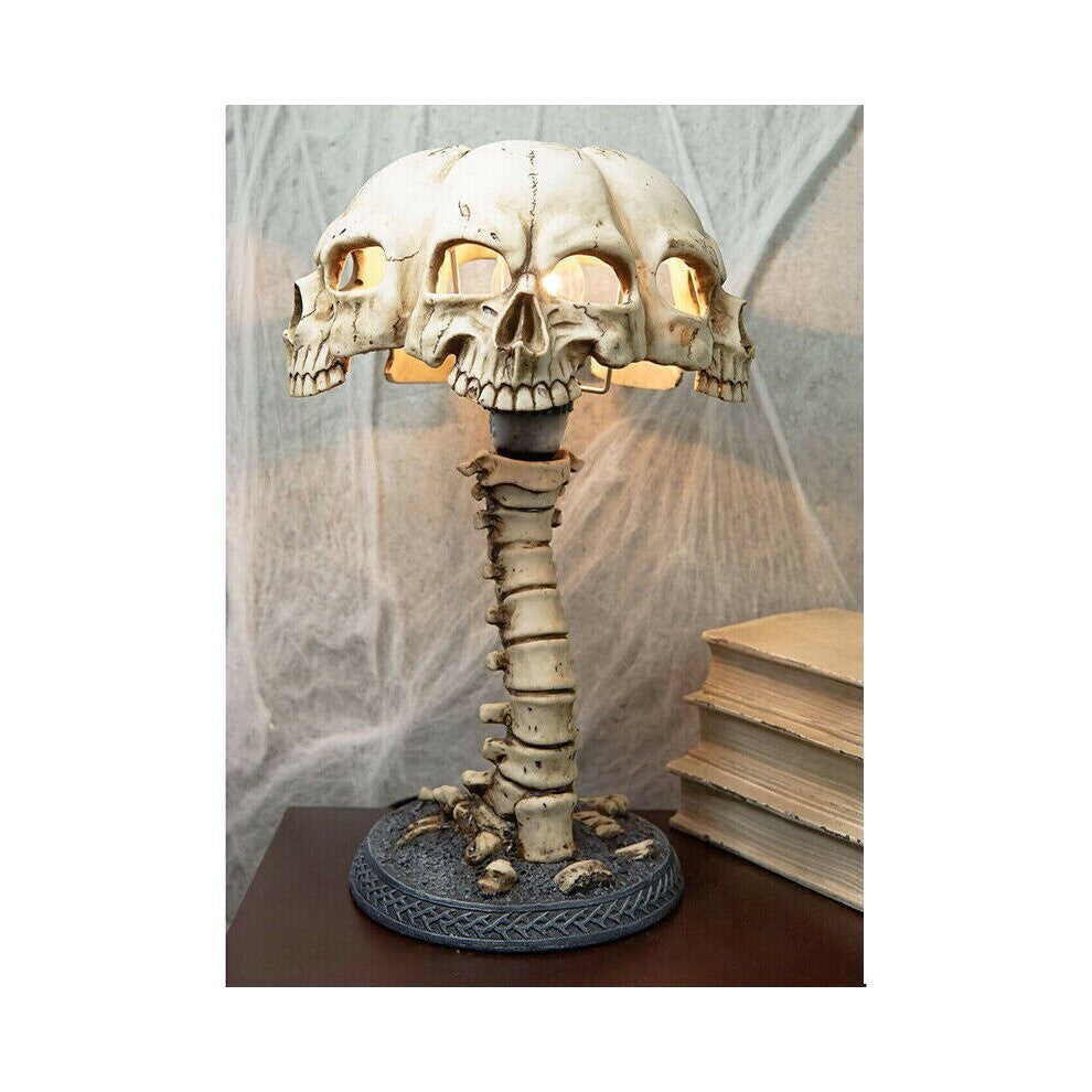 A hand-painted 3D resin skull skeleton desk lamp glowing with eerie light on a dark wooden table decorated for Halloween.